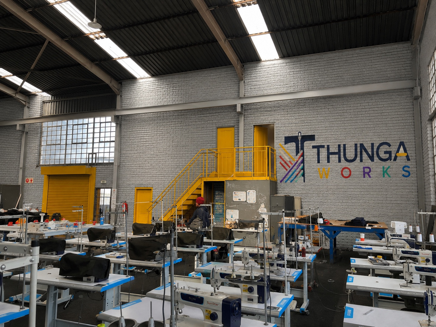 Actual Thunga Works factory with industrial sewing machines and branded production floor