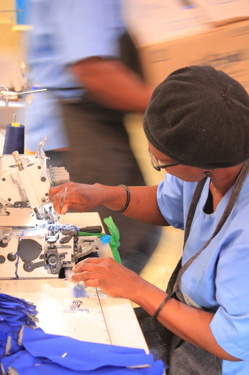 Garment production worker operating an industrial sewing machine at Thunga Works